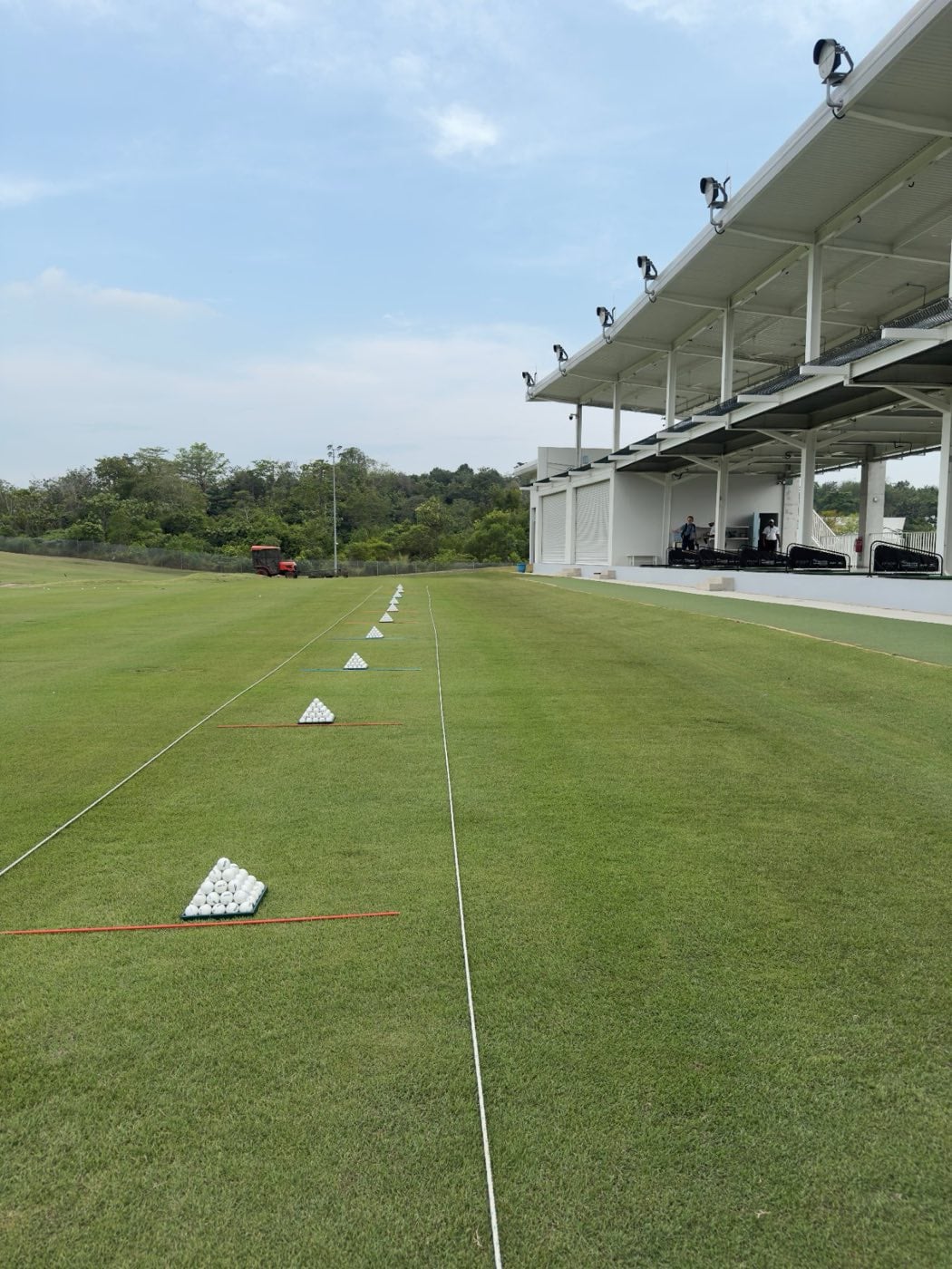 The floodlit, covered driving range bays at Epsom College Malaysia, with practice targets laid out on the grass
