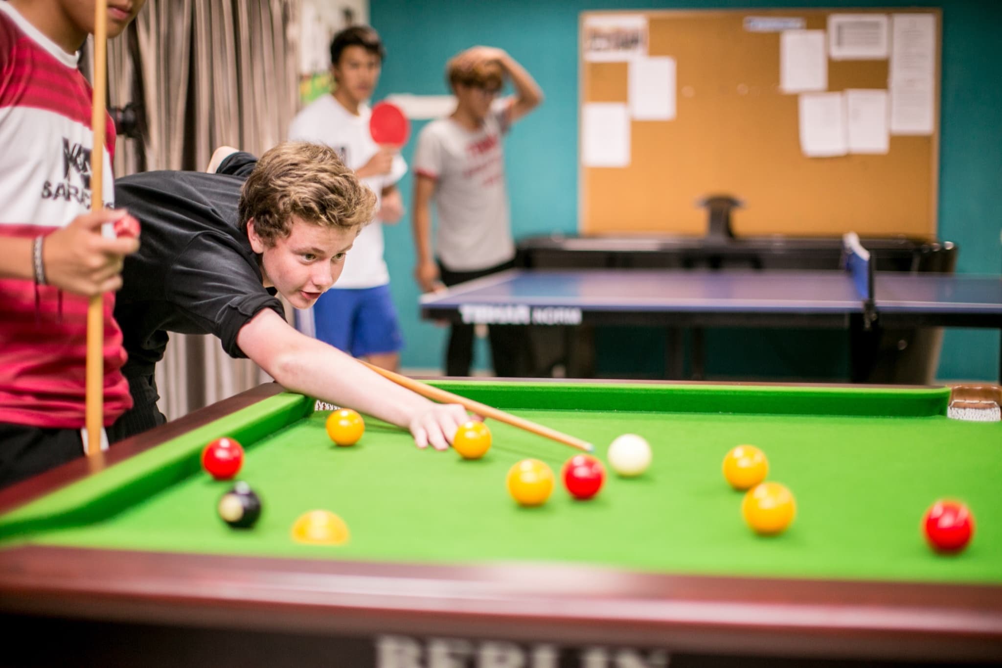 Campers playing pool in the house common room during the evening programme
